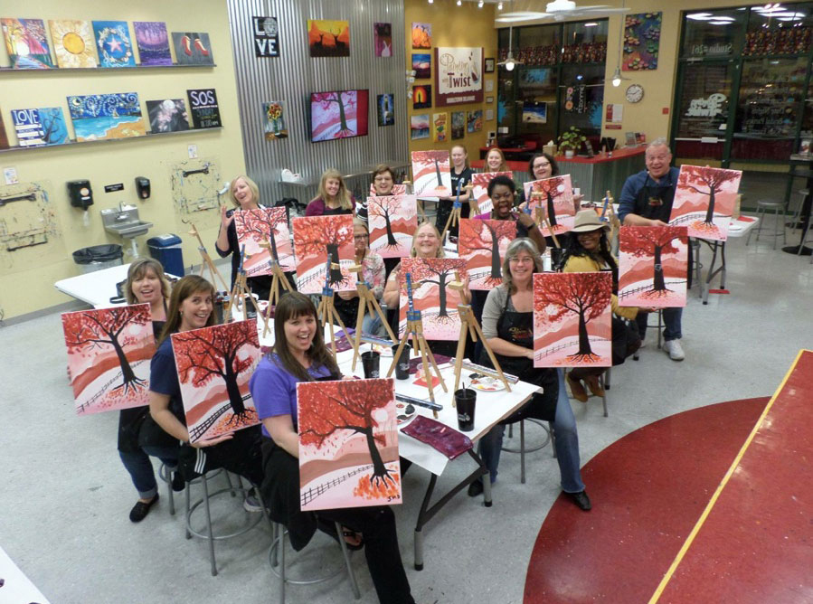 picture of a group of people holding paintings at a painting event.