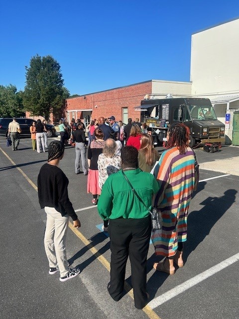 Alt text: "Employees stand in line at a food truck in the parking lot outside the Delaware Office of the Marijuana Commissioner in Dover, participating in a fundraiser for the State Employees' Charitable Campaign.