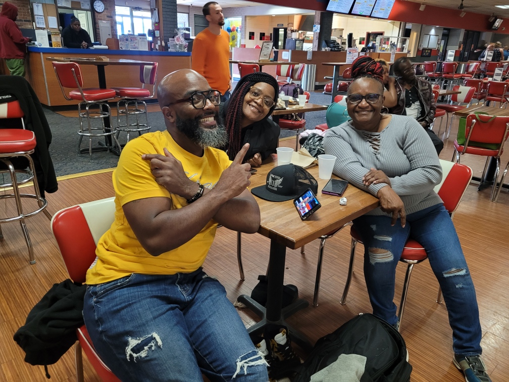 3 People Smiling at a bowling alley table