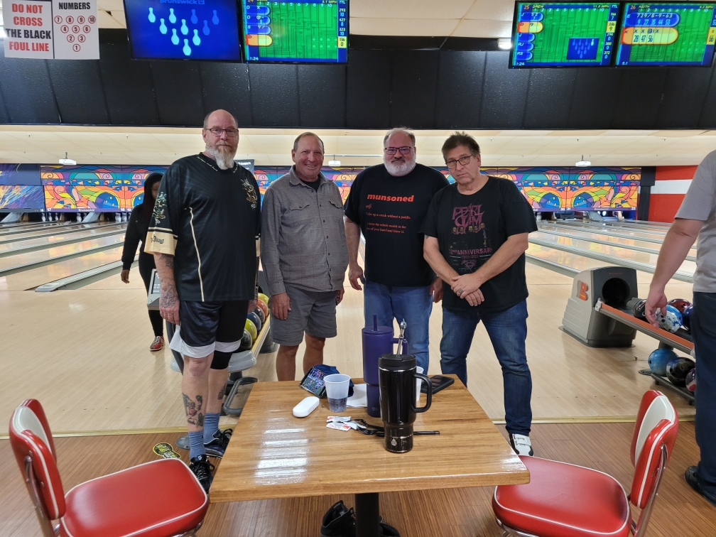 4 people posing for a photo in a bowling alley
